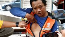 Mototaxikář ukazuje zdravotníkům své zranění z malé exploze v Bangkoku.