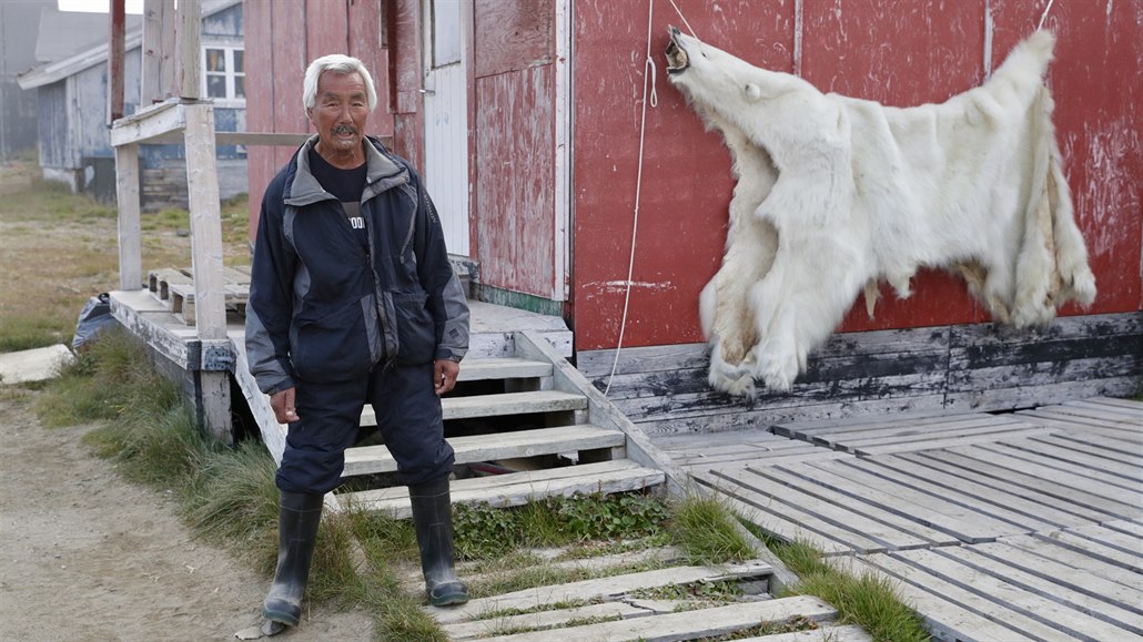 Muž vychází ze svého domu v osadě Kulusuk. V pozadí visí kůže medvěda.