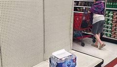 A near-empty water shelf greets shoppers at a store as people rush to buy...