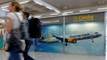 Cestujc prochzejc okolo reklamy na spolenost Thomas Cook na letiti na...