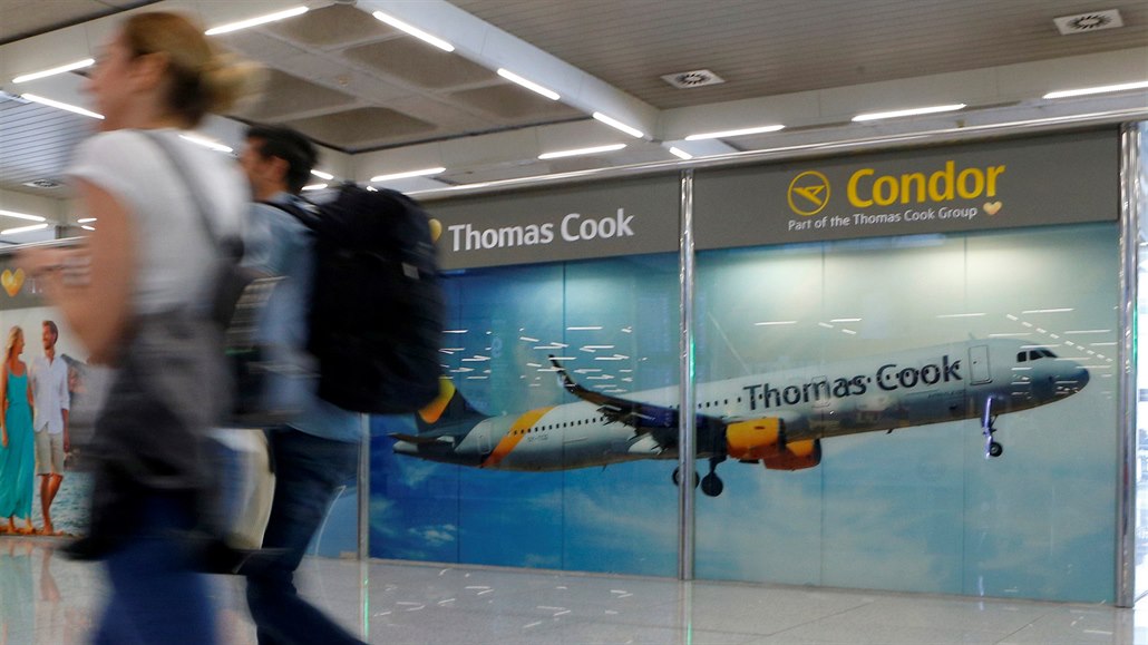 Cestující procházející okolo reklamy na spolenost Thomas Cook na letiti na...