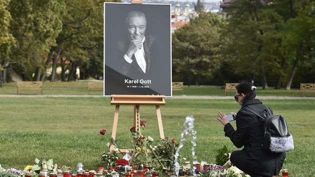 ena fotografuje kvtiny u portrétu Karla Gotta v Kinského zahrad v Praze.