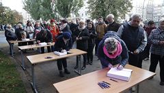 Lidé se zapisují do pipravených kondolenních knih.