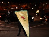 Protestující drí v rukou vlajku YPG.