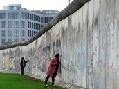 Lidé se dotýkají pozstatk Berlínské zdi, která dlila msto.