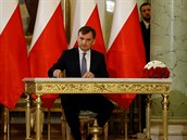 Zbigniew Ziobro podepisuje dokument poté, co byl znovu jmenován ministrem...