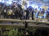 Demonstanti se snaí na lanech dostat z mostu, pod kterým na n ekají...