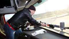 Řidič upravuje palubní jednotky v kabině kamionu na parkovišti u hraničního...
