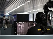Pracovnice na malajském letiti na obrazovce sleduje pasaéry procházející...