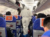 Zdravotníci v ochranných oblecích kontrolují pasaéry letadla (ilustraní foto).