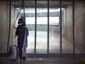 Cestujc s obliejovou maskou prochz plastovmi dlii na stanici metra v...