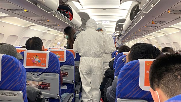 Zdravotníci v ochranných oblecích kontrolují pasaéry letadla (ilustraní foto).
