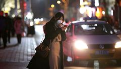 �ena s nasazenou rou�kou hledí do mobilu. Takhle vypadají ulice v Pekingu.