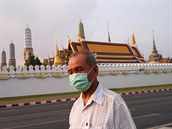 Mu s roukou, kterou se chrání ped koronavirem, prochází ped bangkokským...