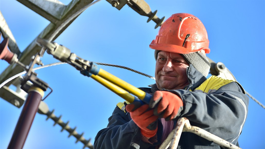 Pracovník energetické spolenosti opravuje zpetrhané vedení v Myenci na...