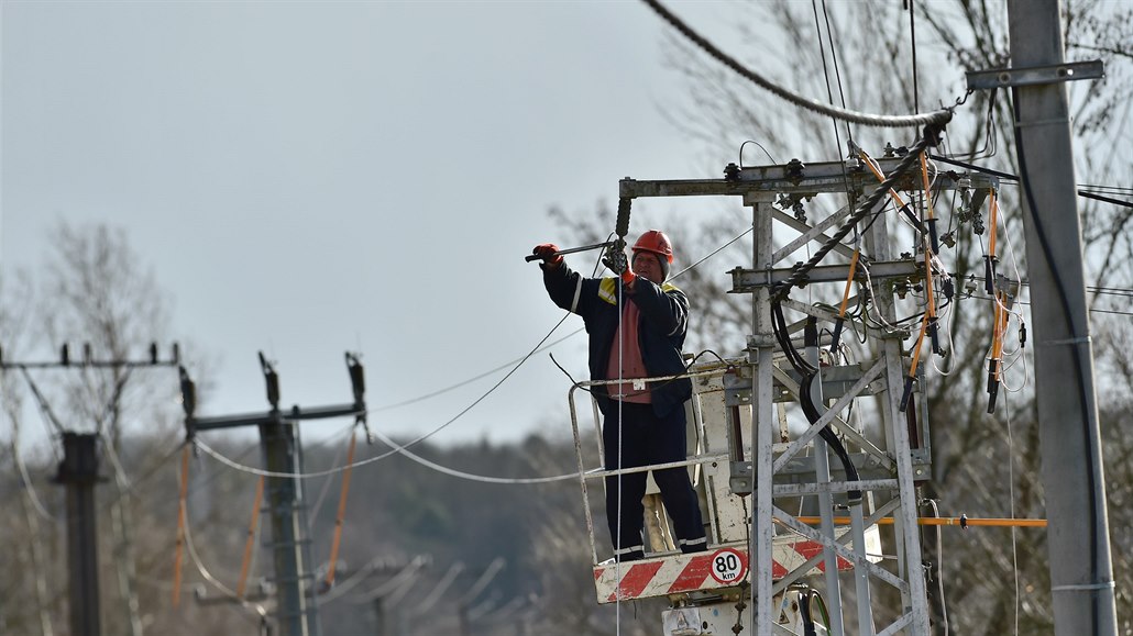 Pracovník energetické spolenosti opravuje vtrem zpetrhané vedení.