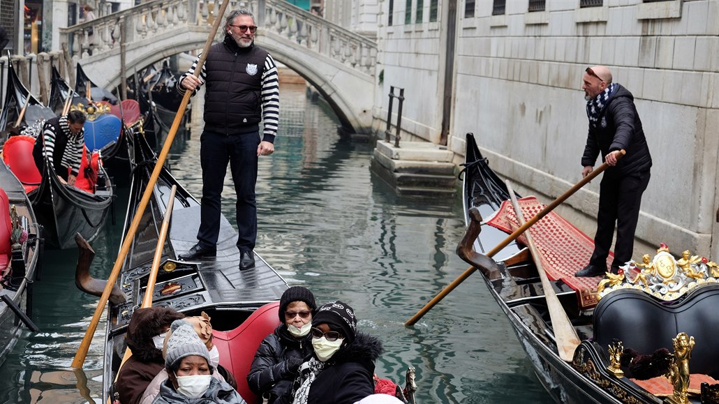 Turisti v Benátkách s roukami na oblieji.