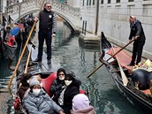 Turisti v Benátkách s roukami na oblieji.