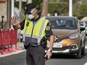Policista ped hotelem na Tenerife se chrání roukou.