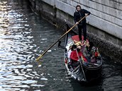 Asijtí turisté na projíce gondolou vodními kanály italských Benátek.