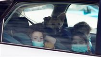 Děti s rouškami na ústech koukají přes okno auta v izraelské Haifě.