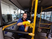 Pracovník úklidové firmy dezinfikuje interiér autobusu dopravce FTL v...