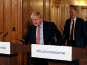Premiér Boris Johnson pichází na tiskovou konferenci, na kterou ho doprovodili...