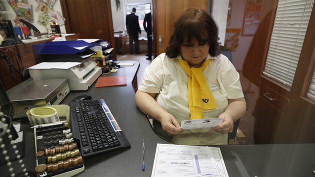 Po�tovní ú�ednice dr�í leták s informacemi o koronaviru.