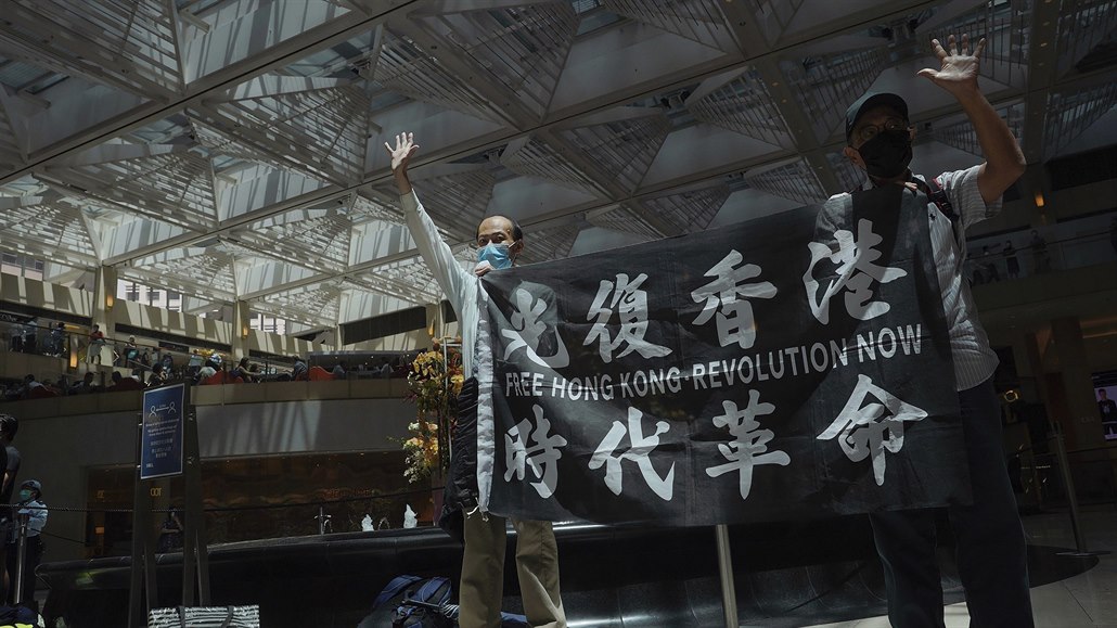 Protestující s vlajkou poadující svobodná Hongkong ukazují gestem na rukou...