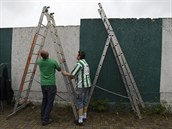 Fanouci si pipravují tafle, aby mohli sledovat zápas za plotem stadionu.
