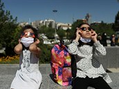 Dvátka pouívají ochrané brýle pi pozorování zatmní Slunce. Tehran, Írán