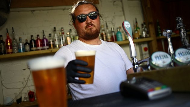Barman podává zákazníkovi pivo sebou v hospod The Landor v londýnské tvrti...
