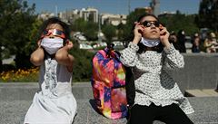 Děvčátka používají ochrané brýle při pozorování zatmění Slunce. Tehran, Írán