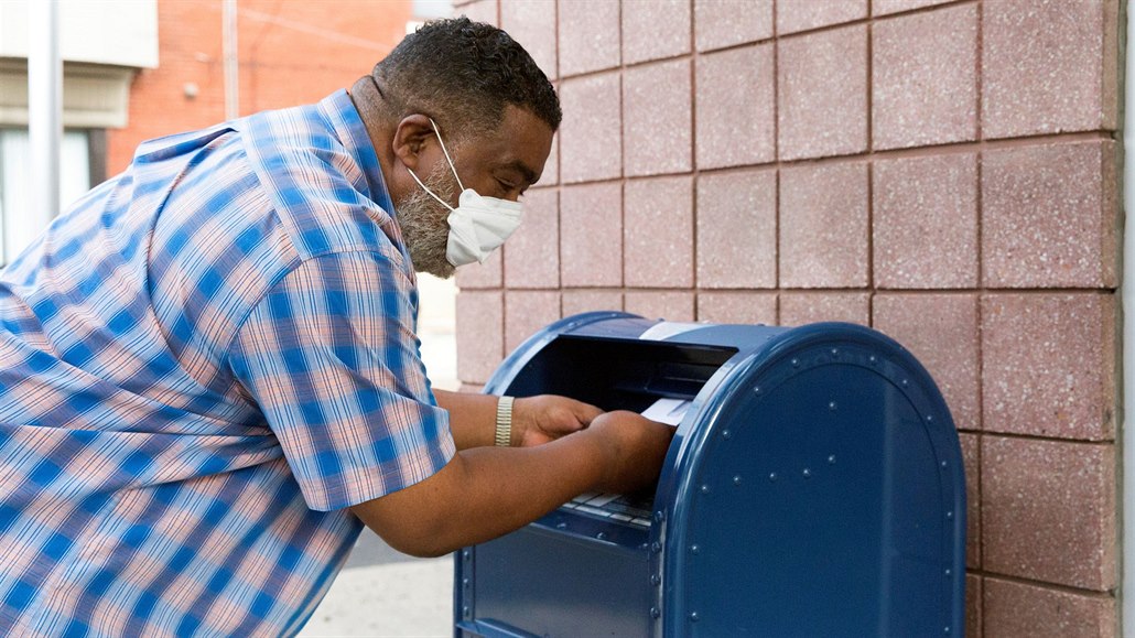 Američan hází poštu do schránky Poštovní služby Spojených států (USPS) v...
