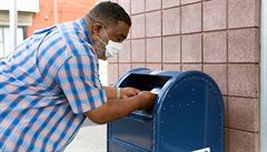 Američan hází poštu do schránky Poštovní služby Spojených států (USPS) v...