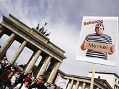 Protestující na transparentu drí fotku Angely Merkelové upravené ve...