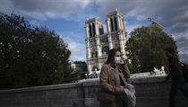 Žena v roušce procházející kolem katedrály Notre-Dame v Paříži.