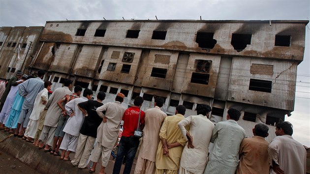 Lidé stojí ped vyhoelou továrnou, kde zahynulo více ne 250 lidí.