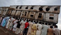 Lidé stojí před vyhořelou továrnou, kde zahynulo více než 250 lidí.