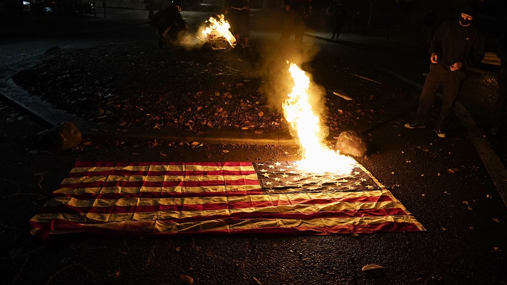 Lidé pozorují hořící americkou vlajku v ulicích Portlandu.