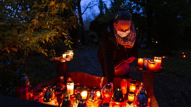 Lidé uctívají památku zesnulých zapálením svíky.
