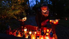 Lidé uctívají památku zesnulých zapálením svíky.