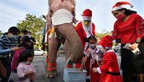 Students receive face masks from an elephant dressed as Santa Claus, in an...
