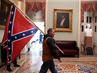 Podporovatel Donalda Trumpa uvnitř budovy Kapitolu třímající konfederační...