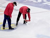 Pracovníci zimního stadionu opravují ledovou plochu.