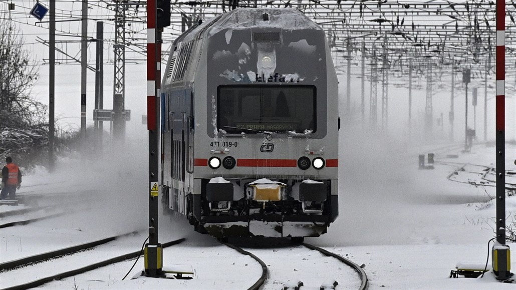 Vlak projídí zasneným nádraím - ilustraní foto. 