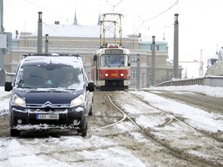 Automobil a tramvaj projdj zasnenou ulic v centru Prahy.