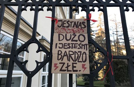 Plakát na plotu polského velvyslanectví v Praze s nápisem Je nás moc a jsme...