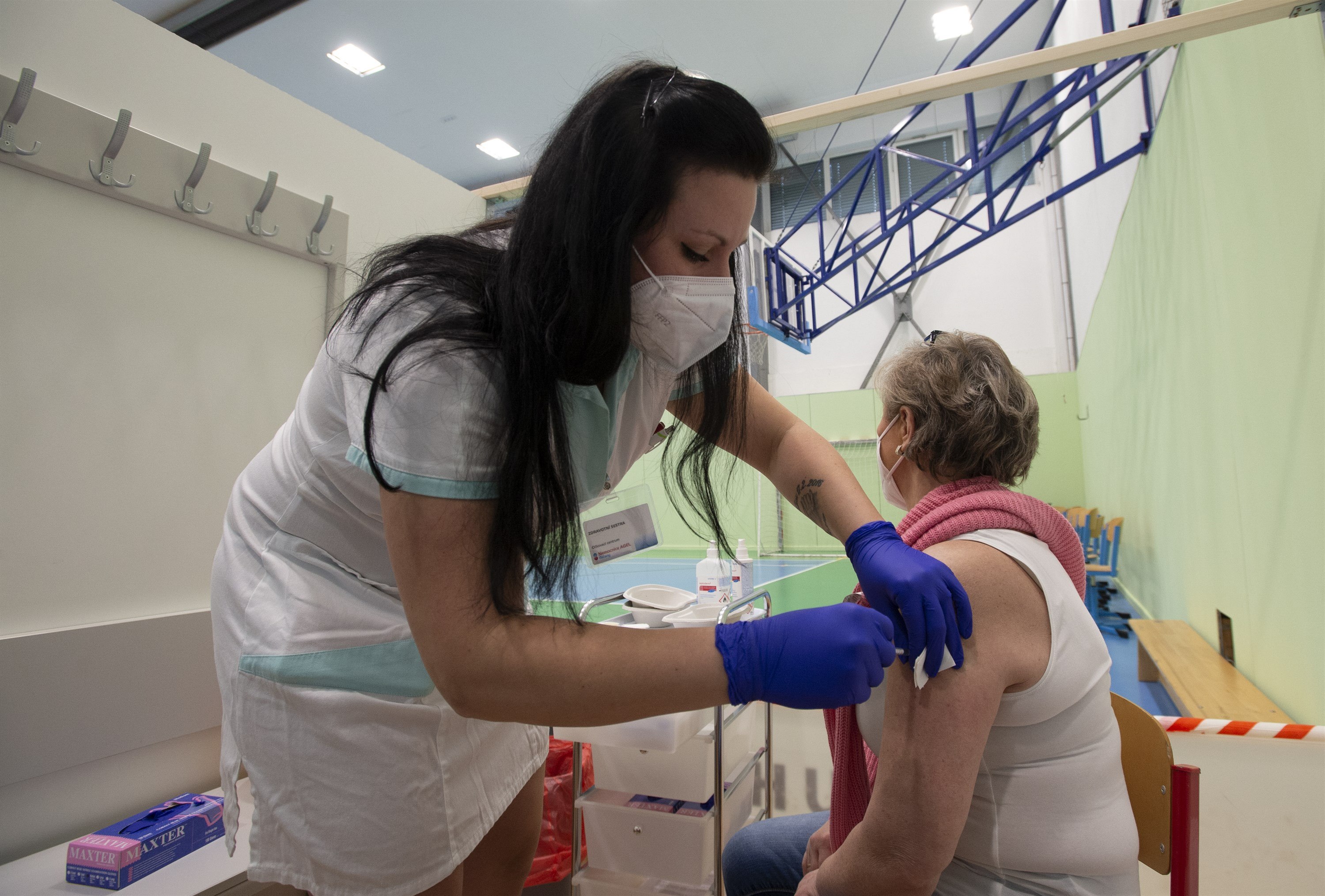 Zdravotnice očkuje klientku v očkovacím centru ve sportovní hale v Říčanech u...