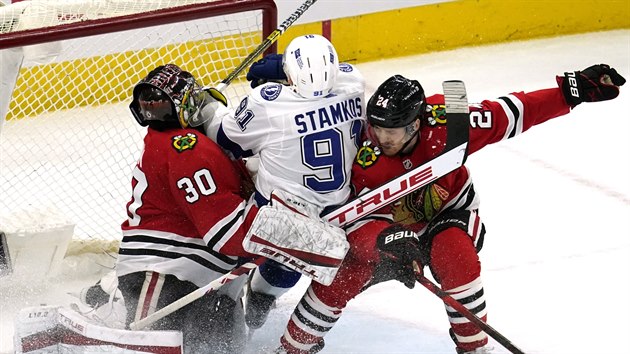 Steven Stamkos (uprosted) z Tampa Bay padá mezi hráe Chicaga Malcolma Subbana...